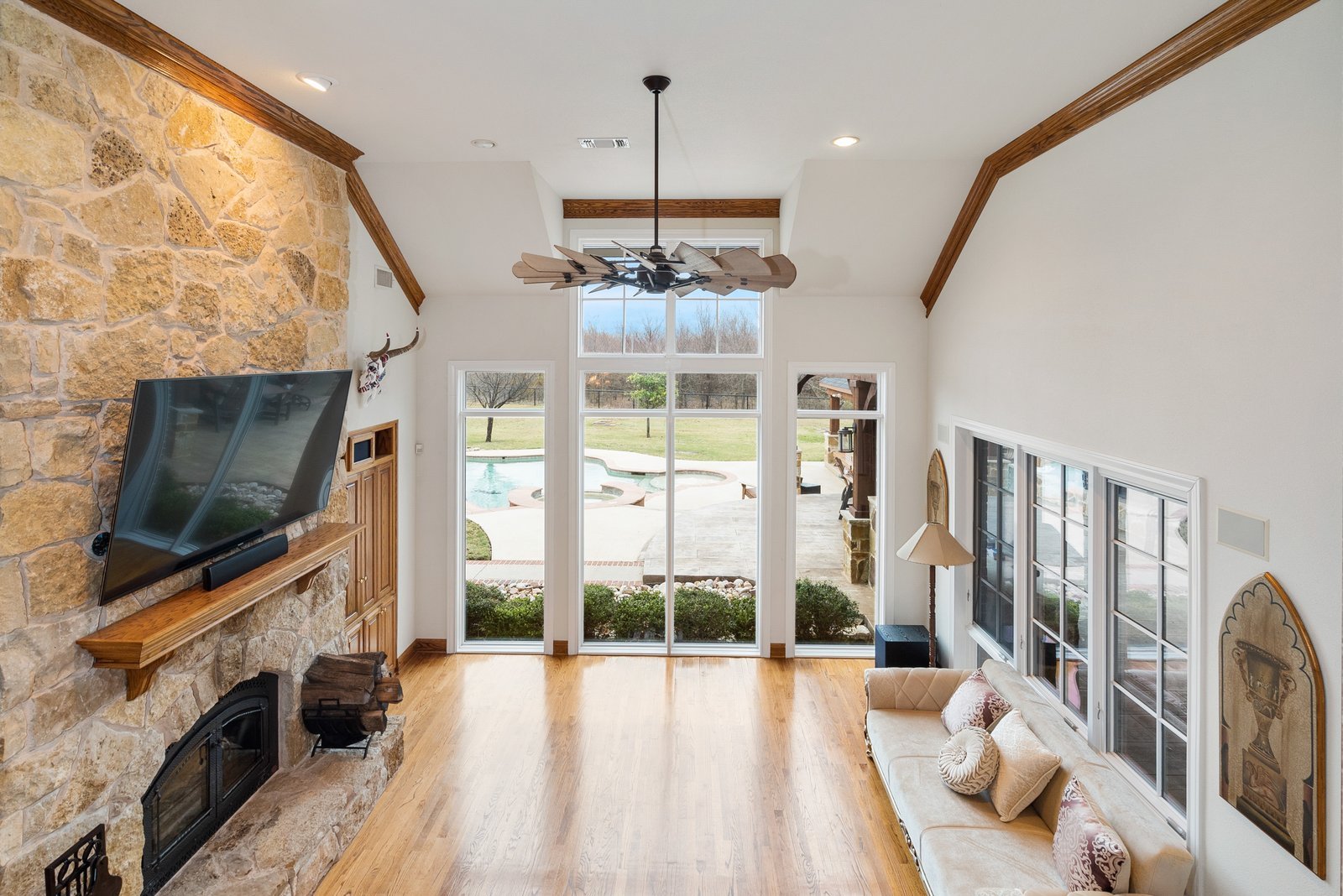 Living room with stone fireplace and pool views